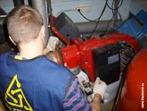 Сотрудник сервисной службы демонтирует на котле комбинированную горелку