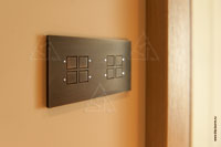 Фото 8-ми кнопочного выключателя CJC Systems серии Lola Flatline на стене в помещении загородного дома