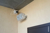 Фото выполненного монтажа камеры видеонаблюдения и аудиоколонки мультирум у входа в дом